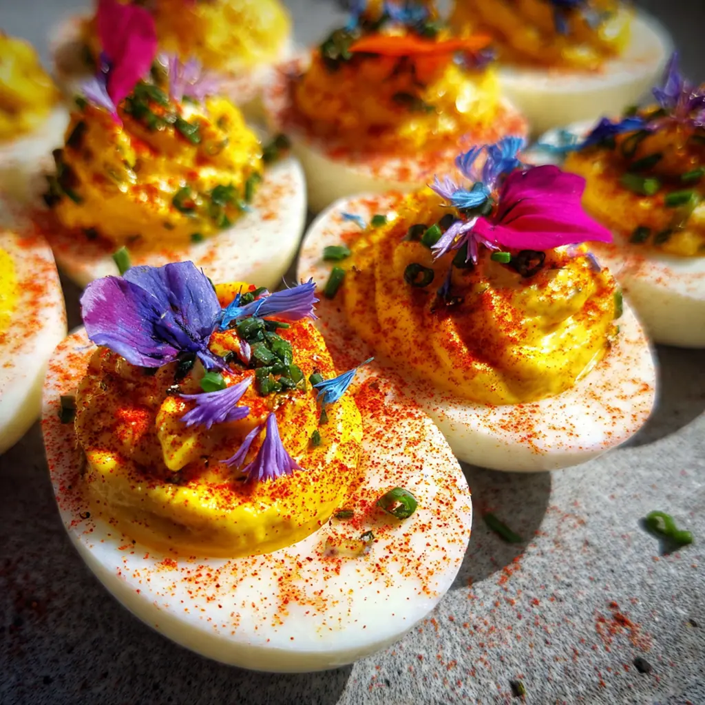 Freshly made Easter Deviled Eggs garnished with paprika and finely chopped herbs on a white platter